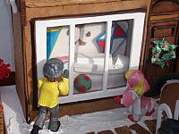 close up of toy shop window with a boy and girl gumpaste figurines looking in