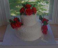 Angle view of red roses on white cake.